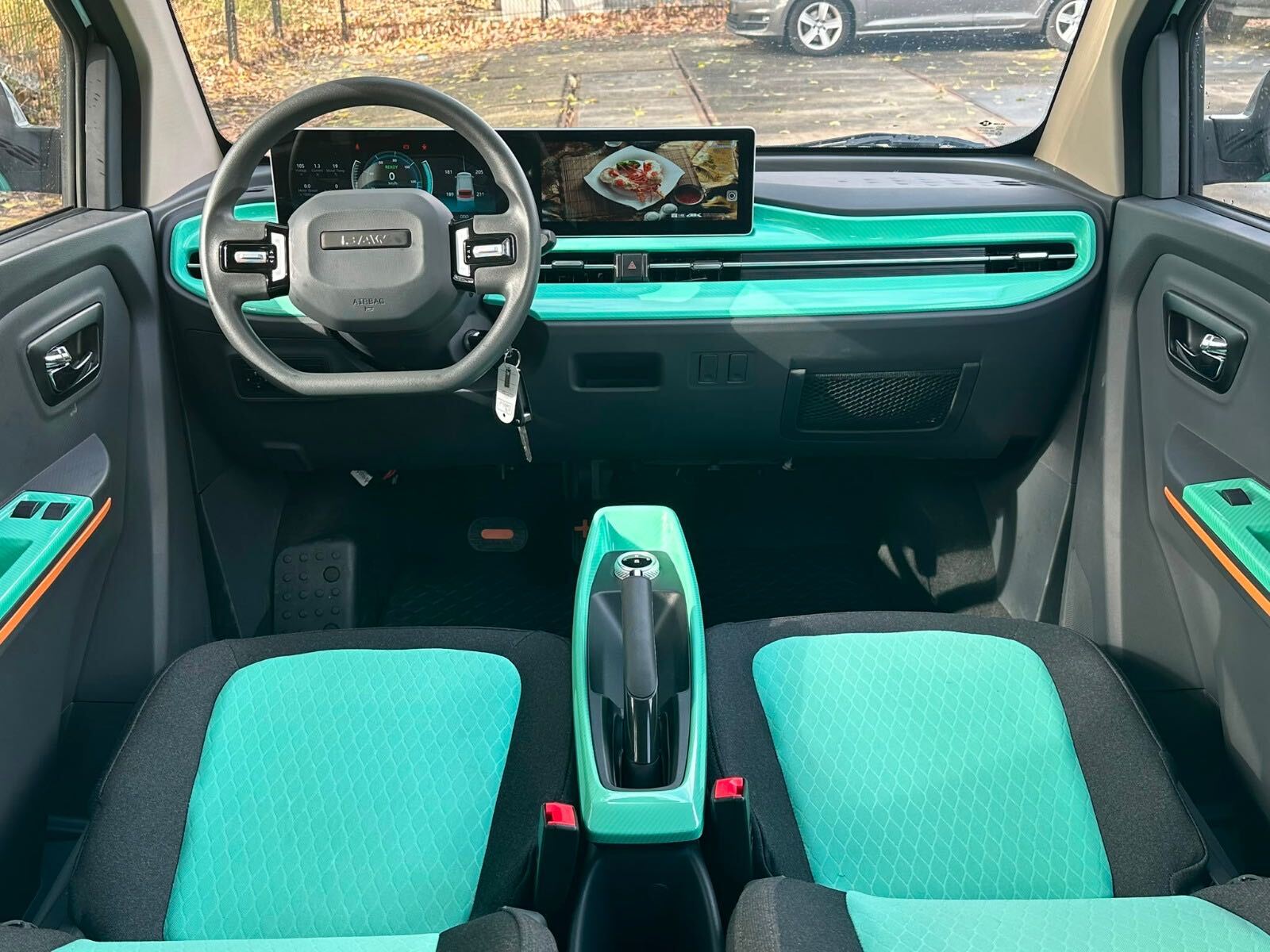 Breed zicht op het dashboard, de twee schermen en het groene interieur van de Liddel City